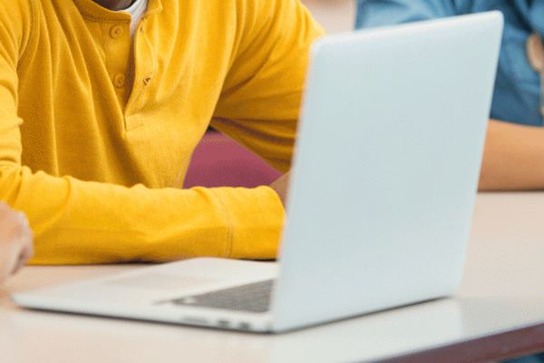 Un ordinateur portable ouvert sur une table de salle de classe.